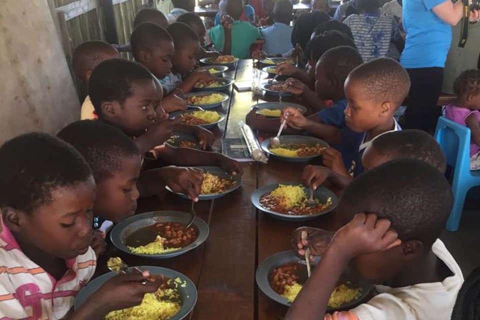 Children eating a meal together at a long table.